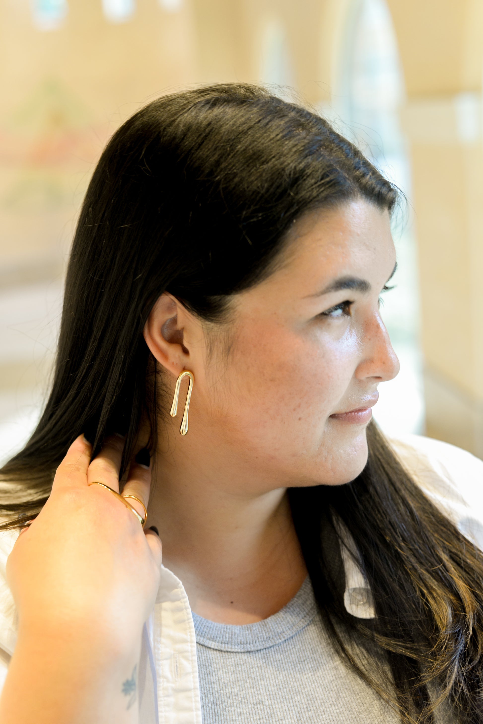 Woman wearing gold hoop earrings with a blurred background
